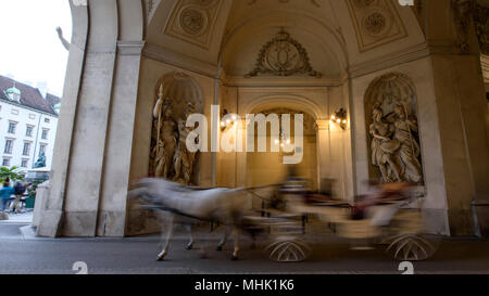 Una carrozza a cavallo passa attraverso il Palazzo di Hofburg di Vienna in Austria. Foto Stock