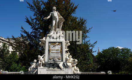 Un uccello vola da Mozartdenkmal o statua di Mozart a Vienna, Austria. Foto Stock