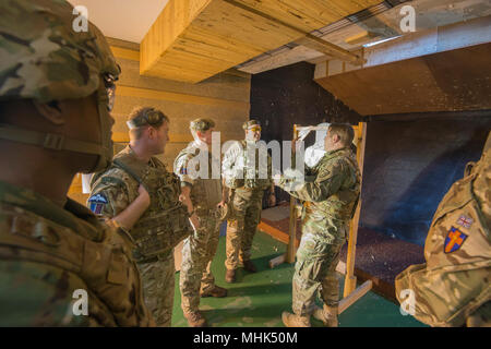 Stati Uniti Army Sgt. William Buttner, assegnato al Bravo Company, le forze alleate Nord battaglione, U.S. Esercito Brigata NATO, assiste le forze del Regno Unito tiro con la M4 carbine durante una multinazionale di evento di formazione su Wingene Air Base, Belgio, 16 marzo 2018. (U.S. Esercito Foto Stock