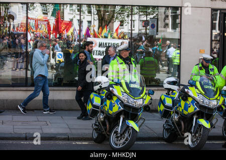 Londra, Regno Unito. Il 1 maggio, 2018. Una riflessione in una finestra dietro un motociclista della polizia di rappresentanti di sindacati e partiti socialista e comunista da molti paesi diversi assemblaggio su Clerkenwell Green per l annuale giorno di maggio marzo a marchio International giorno della festa dei lavoratori. Credito: Mark Kerrison/Alamy Live News Foto Stock