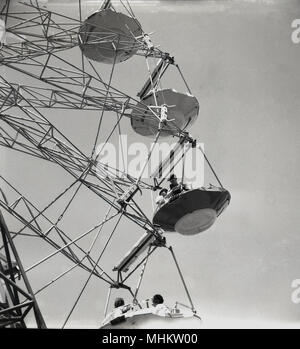 Anni sessanta, storico, persone a cavallo aperto in auto attraverso l'aria su un gigante meccanico rotante ruota, Parco di Battersea, Londra, Inghilterra, Regno Unito. Foto Stock