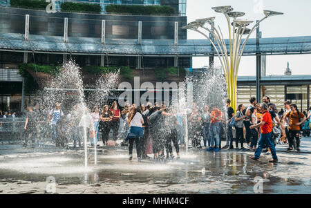 Milano, Italia - 25 Aprile 2018: le persone si bagnano nelle fontane a Gae Aulenti square, circondato da moderni grattacieli, in Porta Nuova quartiere degli affari Foto Stock