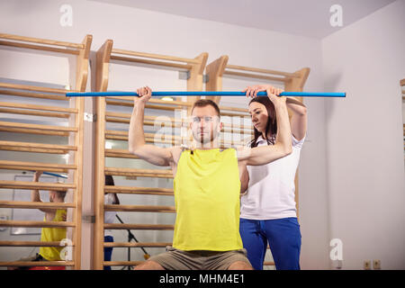 Due persone, che lavorano fuori, praticando fisioterapista correggendo, chekcing paziente, corpo superiore, posteriore. Foto Stock