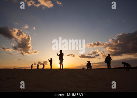 NC01724-00...CAROLINA DEL NORD - Le persone raccolgono sulle più alte dune di sabbia sulla costa orientale a guardare il tramonto a Jocky Crinale del Parco dello Stato nazionale l naturale Foto Stock