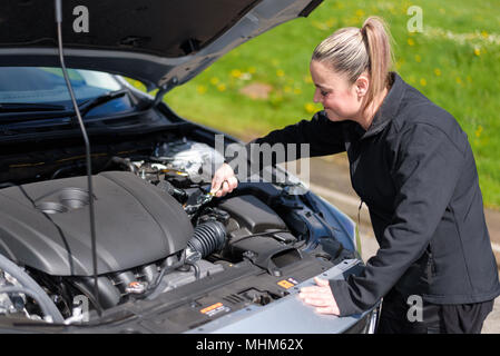 Una donna meccanico la riparazione di un motore di auto in strada Foto Stock