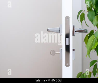 Primo piano della serratura con la chiave. Moderne maniglie cromate. Luce a parete con spazio libero in background. Foto Stock