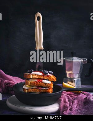 Toast alla francese con frutti di bosco, sciroppo e panna acida in un nero ghisa padella, close up Foto Stock