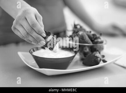 Primo piano sulla felice giovane donna di mangiare fragole con yogurt in cucina Foto Stock