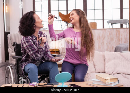 Allegro storpi donna e bambina per divertirsi durante il trucco Foto Stock