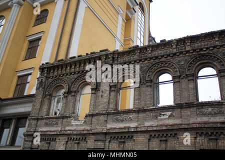 Parete di mattoni di facciata di rovinato il vecchio edificio di fronte della moderna casa gialla Foto Stock