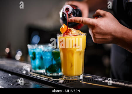 Il barista è la preparazione di cocktail arancione sul bancone del bar Foto Stock