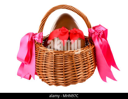 Unwrapped chocolate easter egg with bow in a wicker basket Foto Stock