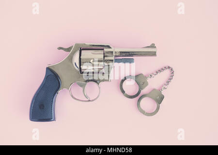 Pistola con piccole manette piana minima laici concetto creativo. Foto Stock