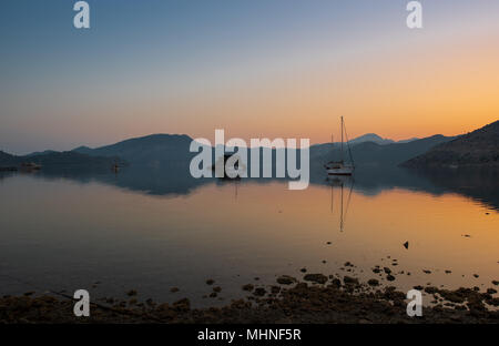 Barche all'alba, colline riflessi nell'acqua Foto Stock