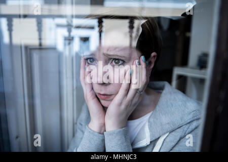 Giovani belle premuto infelice donna caucasica guardando preoccupata e triste attraverso la finestra a casa. sensazione inutile e nel dolore. primo piano. Depressi Foto Stock