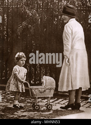 Giovane principessa Elisabetta (Più tardi la Regina Elisabetta II) (1926-) con il suo primo toy pram in i motivi del suo genitore della casa di Piccadilly con la sua bambinaia. Data: 1928 Foto Stock