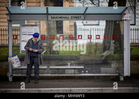 Glasgow in Scozia, Sauchiehall Street, Newton luogo rifugio di bus con il vecchio gentleman Sikh in attesa di un autobus Foto Stock