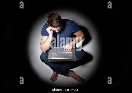 Giovane uomo utilizzando laptop in piscina di luce Foto Stock