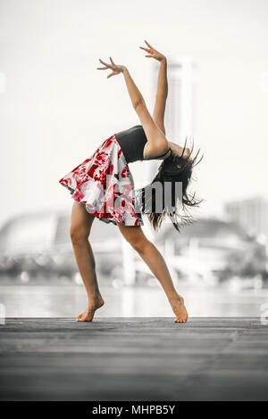 Bella giovane flessibile Woman Dancing indossando abito rosso Foto Stock