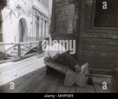 Uomo che dorme su una panchina in una strada laterale, Venezia, Italia Foto Stock