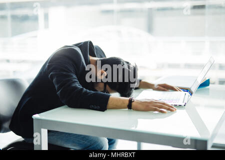 Commerciante indiano dormire oltre il portatile in ufficio Foto Stock