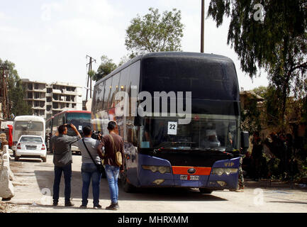 Damasco. Il 3 maggio, 2018. Gli autobus che trasportano i ribelli e le loro famiglie sono visibili nella periferia meridionale di Damasco, Siria, il 3 maggio 2018. Un totale di 32 gli autobus che trasportano centinaia di ribelli e le loro famiglie cominciarono a lasciare la città di Yalda, Babila e Beit Sahem giovedì per il ribelle-held aree nel nord Siria nel quadro di una trattativa tra alcuni ribelli e le forze governative. Credito: Xinhua/Alamy Live News Foto Stock