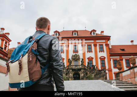 Un viaggiatore con uno zaino guarda l'attrazione turistica. Il turista guarda al castello nella Repubblica Ceca. Visite turistiche. Foto Stock