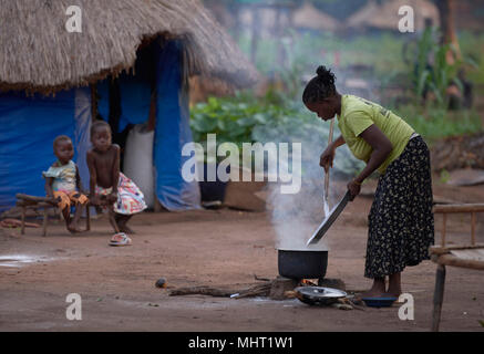 Una donna che cuoce il cibo per la sua famiglia in un campo per sfollati interni in Riimenze, Sud Sudan. Foto Stock