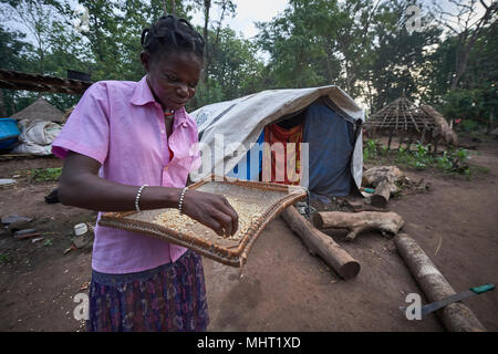 Una donna spostato dal conflitto prepara il cibo da cuocere in un campo per sfollati interni che si è formata attorno a una chiesa in Riimenze, Sud Sudan. Foto Stock