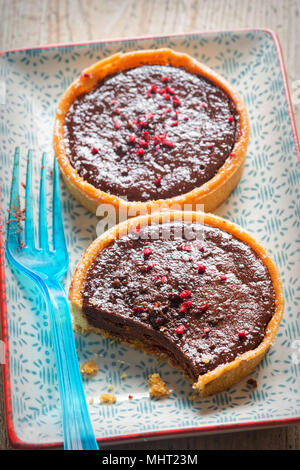 Lampone e cioccolato fondente tart. Tutto il burro crostata di pasta con ripieno di cioccolato e lamponi centro conserva, finito con lampone e cioccolato Foto Stock