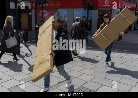 Due uomini trasportare scomodi, scatole lunghe lungo Oxford Street, 1 maggio, a Trafalgar Square a Londra, Inghilterra. Foto Stock