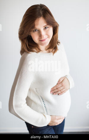 Attesa, la maternità, il concetto di famiglia. vi è un adorabile donna incinta e si sta preparando ad essere una madre, ha un aspetto davvero felice e il suo sorriso è incantevole e affascinante Foto Stock