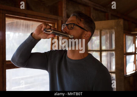 Uomo di bere whisky in log cabin Foto Stock