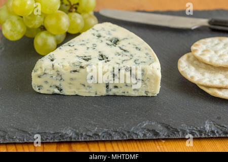 Stilton Formaggi a Muffa Blu cuneo vicino sul nero ardesia di formaggi con il fuoco selettivo Foto Stock