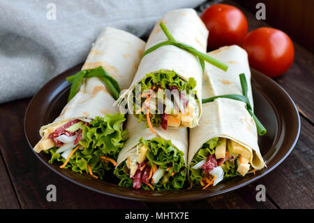 Antipasto di pita (lavash) ripieni con: salumi, formaggi, sottaceti, carote, salsa, verdi. Shawarma Foto Stock