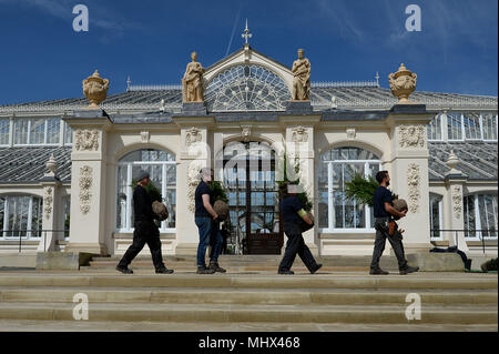 Orticoltori trasportare alberelli passato l'ingresso della casa temperate a Kew Gardens di Kew. Foto Stock