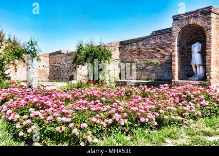 Scorcio del cortile wirh giardino di rose e rovine della Domus della Fortuna Annonaria - una ricca casa a Ostia Antica - Roma Foto Stock