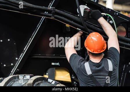 Lavoratore assembla il trattore o macchina mietitrebbiatrice a grandi macchinari impianti. Concetto industriale di produzione dei macchinari pesanti Foto Stock