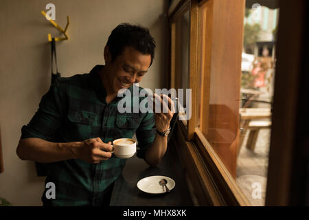 Imprenditore parlando al telefono cellulare mentre un caffè presso la caffetteria Foto Stock