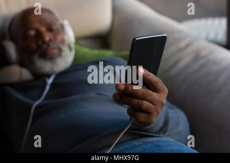 Senior uomo che ascolta la musica sullo smartphone Foto Stock