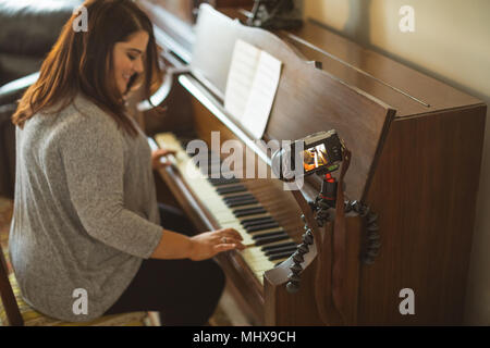Bellissima femmina vlogger suonando piano Foto Stock