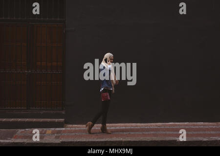 Il hijab donna parlando al telefono cellulare mentre camminando sul marciapiede Foto Stock