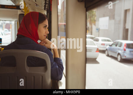 Il hijab donna che guarda attraverso la finestrella in bus Foto Stock