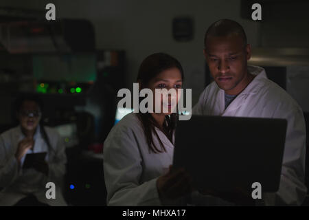 Gli scienziati a discutere su laptop Foto Stock