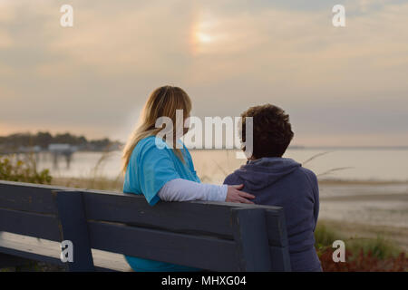 Donna e accompagnatore godendo tramonto dal mare Foto Stock