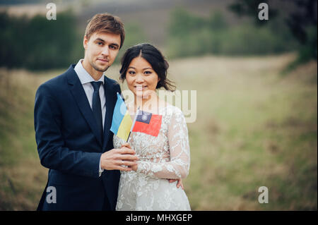 Lo sposo e la sposa tenendo le bandiere di Ucraina e Taiwan Foto Stock