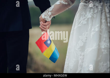 Lo sposo e la sposa tenendo le bandiere di Ucraina e Taiwan Foto Stock