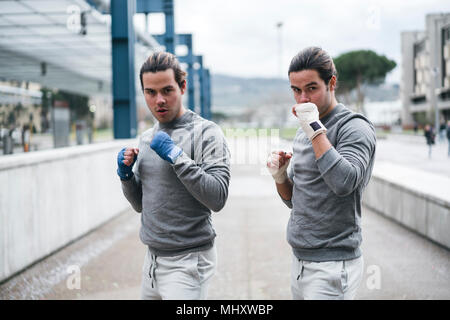 Identica maschio adulto twin boxer formazione all'esterno, combattimento posizione ritratto Foto Stock