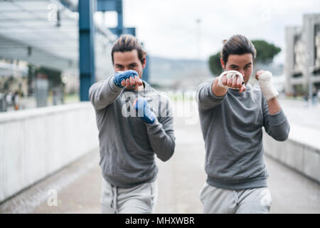 Identica maschio adulto twin boxer formazione all'esterno, combattimento posizione ritratto Foto Stock