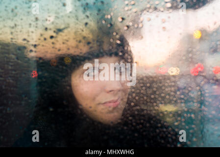 Donna che guarda fuori della pioggia schizzato finestra Foto Stock